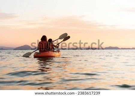 Happy group kayaking at sunset by the sea