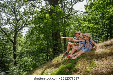 Happy group of kids, boys, girl sit, pointing in a forest hill in summer scout camp on their vacations - Powered by Shutterstock