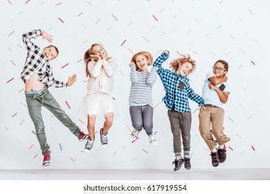 Happy Group Of Kids Jumping In A Room With Decorative Tape On The Wall