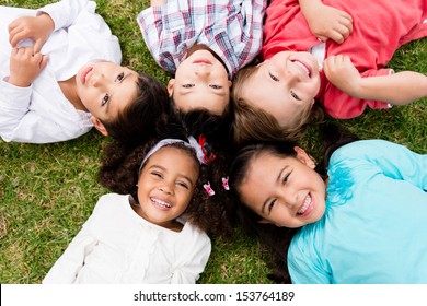 Happy Group Of Kids Lying On The Floor In A Circle 