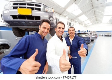 Happy group of mechanics with thumbs up at a car garage - Powered by Shutterstock