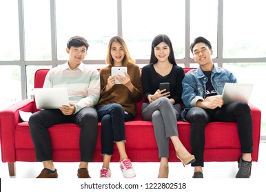 Happy group of students using digital devices and looking at camera gesture in university atrium social networking using several tech devices.Technology , education and teenage concept.