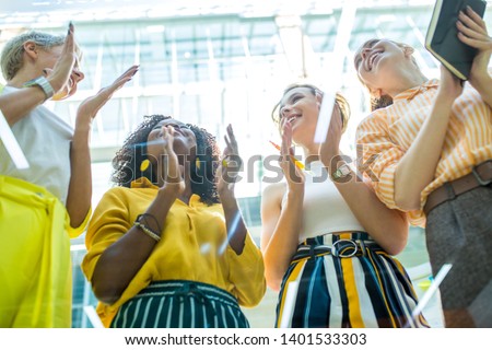 Happy group of talented successful young businesswomen, designers clapping in office, low view. good job, good presentation, winers are celebrating their victory