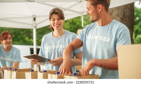 Happy Group of Volunteers Helping in a Local Community Food Bank, Preparing Free Meal Rations to Low-Income People in a Park on a Sunny Day. Charity Workers Work in Humanitarian Aid Donation Center. - Powered by Shutterstock