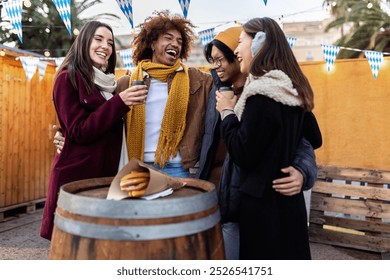 Happy group of young friends drinking hot drink at christmas market on winter. Friendship and vacation concept. - Powered by Shutterstock