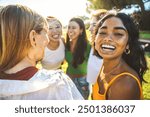 Happy group of young women hugging together outside - Cheerful black girl smiling at camera outdoors - Friendship and female community concept with multicultural girls having fun hanging out together