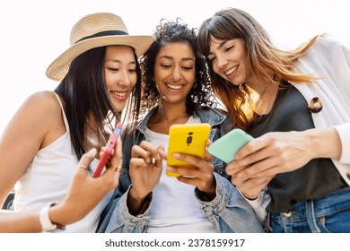 Happy group of young women using smartphones outdoor. Three diverse female friends connected on mobile phone device, watching social media content online. Technology lifestyle concept. - Powered by Shutterstock