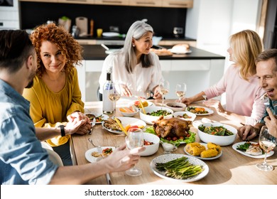 Happy Guests Chatting At The Thanksgiving Party At The Table