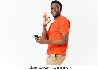 Happy Guy Of African Appearance Gesturing With His Hands And Holding A Mobile Phone 