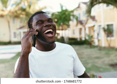 Happy Guy Of African Appearance Talking On The Phone And Laughing At Camera Wide Open Mouth