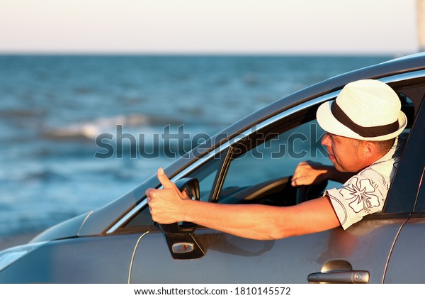 Happy guy in the car by the sea in nature on\
vacation travel