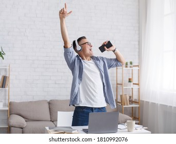 Happy guy enjoying new audio track playing in digital application and sings in smartphone in interior of living room, copy space - Shutterstock ID 1810992076