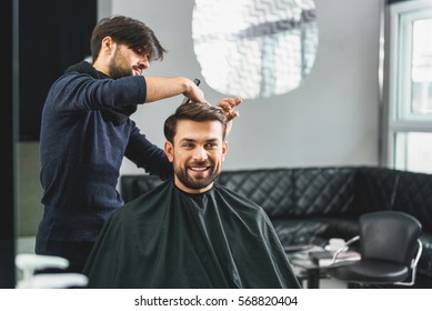 Happy guy getting haircut by hairdresser