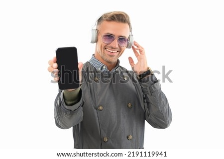 Happy guy in headphones showing smartphone. Listening to music with smartphone. Mobile music