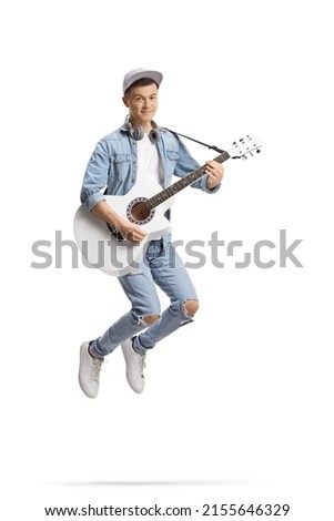 Happy guy jumping and playing an acoustic guitar isolated on white background