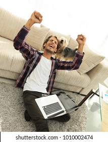 happy guy with laptop jubilant in spacious living room.