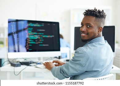 Happy guy looking at you while sitting by workplace and working with software - Shutterstock ID 1155187792