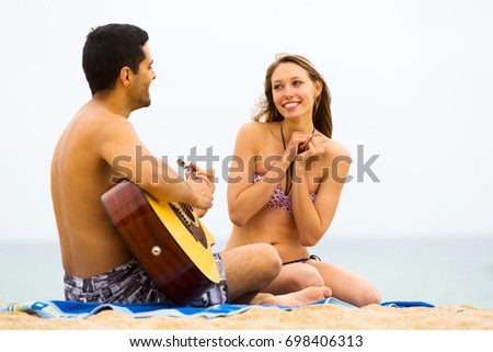 Happy guy plays guitar for his girlfriend. Focus on the woman