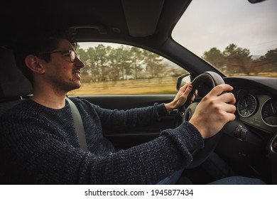 Happy Guy Sitting Driving A Car With Two Hands On The Steering Wheel