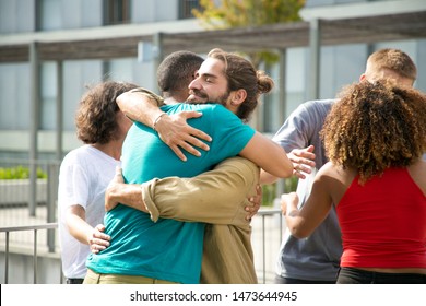 Happy Guys In Casual Hugging Each Other. Close Friends Meeting On Outdoor Building Terrace, Embracing And Greeting Each Other. Bonding Concept