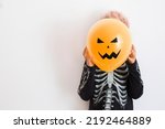Happy Halloween background with orange balloon with Halloween face and blonde boy  in Halloween costume 