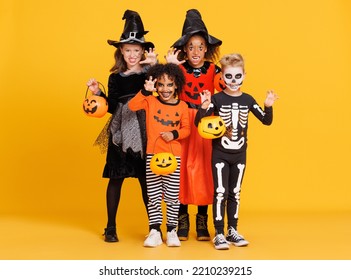 Happy Halloween! Cheerful kids in carnival costumes and makeup make a terrible gesture on bright colored yellow background - Powered by Shutterstock