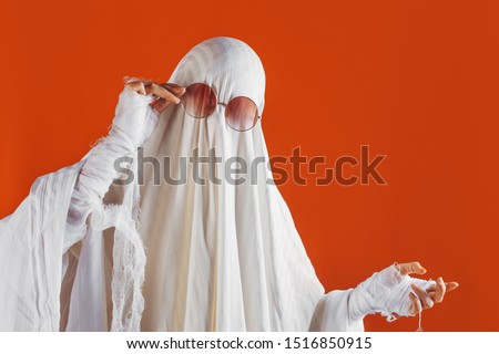 Happy Halloween. Cute funny Ghost on a bright orange background. Sheet Ghost costume, Halloween party carnival. Lovely ghost