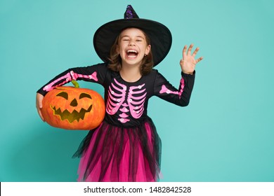 Happy Halloween! Cute little witch with a pumpkin on turquoise background.