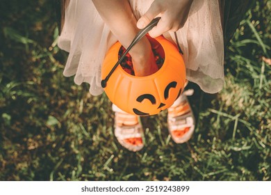 Happy Halloween day. A little cute girl in a witch costume is holding her pumpkin Jack's bucket with candy in her hand. Halloween party, kids trick or treat, close-up. - Powered by Shutterstock