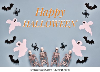 Happy Halloween greeting card. Flat lay composition with text Happy Halloween with the ghosts, spiders, skeletons and bats on light blue background. Postcard for holiday. Top view  - Powered by Shutterstock