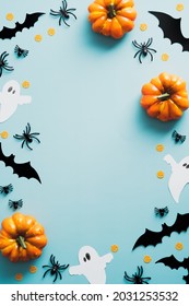 Happy halloween holiday concept. Halloween decorations, bats, ghosts, spiders, pumpkins on blue background. Halloween party poster mockup with copy space. Flat lay, top view, overhead.