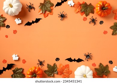 Happy Halloween holiday concept. Halloween decorations, pumpkins, bats, ghosts, spiders, maple leaves on orange background. Halloween party invitation card mockup. Flat lay, top view