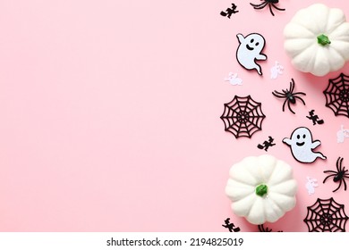 Happy Halloween holiday concept. Halloween flat lay composition with cute decorations, pumpkins, spiders, ghosts, web on pastel pink background. Top view with copy space.