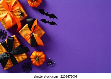 Happy Halloween Holiday Concept. Flat Lay Gift Boxes, Orange Pumpkins, Bats, Spiders On Purple Background. Halloween Greeting Card Template.