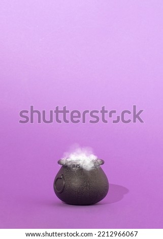 Happy Halloween holiday concept. Witch's cauldron filled with Magical potion. Copy space card, top on purple background.