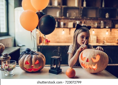 Happy Halloween! Little cute girl is preparing for Halloween. Having fun with pumpkins on kitchen with cat Halloween makeup. - Powered by Shutterstock