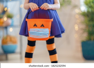 Happy Halloween! Little kid with a basket for sweets  wearing face mask protecting from COVID-19. - Shutterstock ID 1825232594