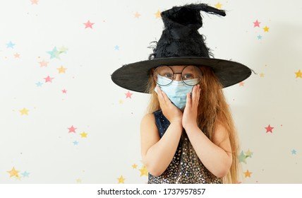 Happy Halloween On Quarantine Coronavirus Pandemic. Little Girl Child In Witch Carnival Costume And Face Protection Mask.