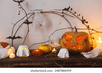 Happy Halloween! Scary pumpkin, glowing ghosts, spiders and bats on table. Halloween decor with spooky Jack o lantern and candles, space for text. Trick or treat - Powered by Shutterstock