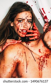 Happy Halloween. Terrifying zombie couple. Blood is flowing down the neck, bite marks are visible. A terrible Halloween episode, the girl bites her boyfriend by the neck, with blood on her face and
