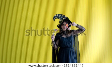 Happy halloween vivid young women catch candy booth 2 hands in black witch , women cute be joyful 
Halloween costume on party over yellow background