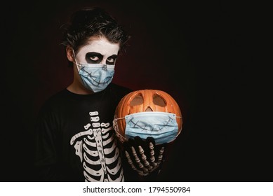 Happy Halloween.kid Wearing Medical Mask In A Skeleton Costume With Halloween Pumpkin Over Dark Background