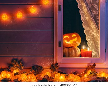 Happy Halloween! The Window Of A House Decorated For The Holiday. Pumpkins, Garland, Candles And Autumn Leaves.