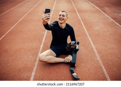 A Happy Handicapped Runner With Artificial Leg Sitting On Running Track And Taking A Selfie.