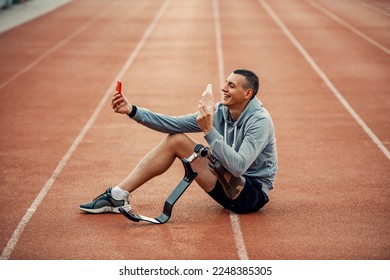 A happy handicapped sportsman with prosthetic leg taking selfie with bottle of water at stadium. - Powered by Shutterstock