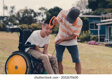 Happy handicapped teenager boy on wheelchair and parent with outdoors activity on lawn, Lifestyle of disability kid with happy family time in sweet home, Diverse family concept.
