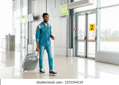 Happy Handsome African American Man Walking With Suitcase In Airport