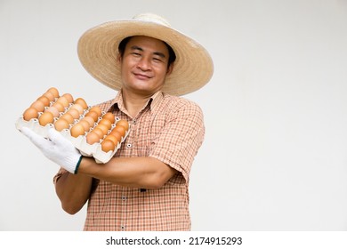 Happy handsome Asian man farmer holds  tray of fresh chicken eggs. Concept : organic farming. Sustainable and sufficiency lifestyle. Farmer raises chickens for eggs to cook in family and sell.  - Shutterstock ID 2174915293
