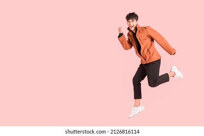 Happy handsome Asian man in fashionable clothing and jumping doing winner gesture isolated on pink background. Portrait of young male cheerful confident and excited jump in air and smile in studio. - Shutterstock ID 2126816114