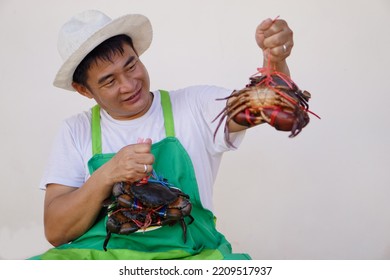 Happy Handsome Asian Man Seafood Merchant Wears White Hat, Green Appron, Shows Crabs. Concept : Owner Small Business. Local Food Products.                 